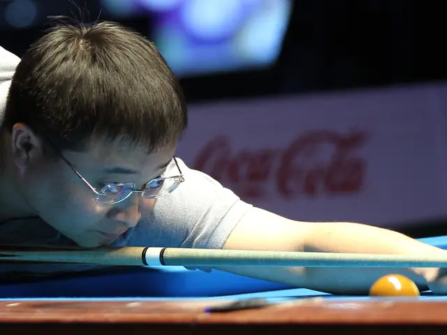 In the image, a man is playing snooker game and the background is blurry.