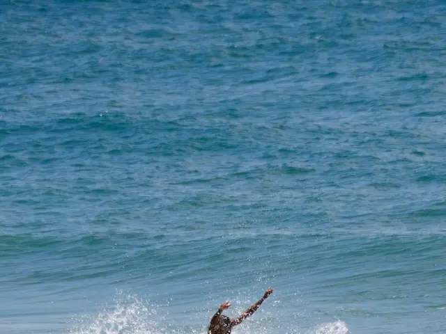 In the image there is water. Also there is a man standing on the surfboard and surfing on a wave.