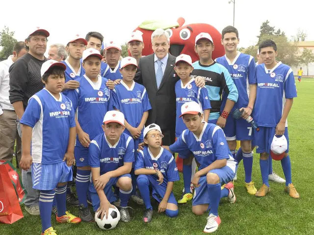 In the picture we can see some boys and few men are standing, and a man who is wearing a blazer,...