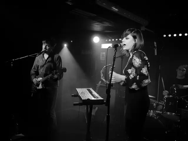 In this image i can see a man and a woman the man standing here is holding a guitar and singing in...