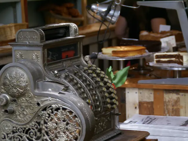 In this picture I can see a machine, there are books, there are cakes on the cake stands, there are...