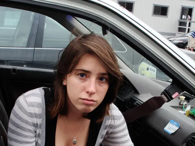 In this image i can see a woman is holding a cloth and sitting in a car.