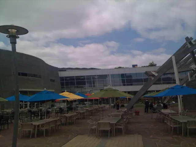 This is a picture of a resort. In the foreground of the picture there are chairs, tables, umbrellas...