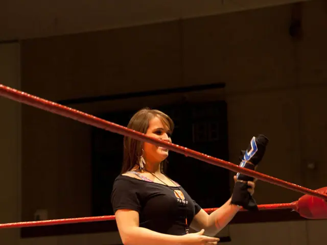 In this picture we can see a woman in a boxing ring and holding a cloth with her hand and smiling...