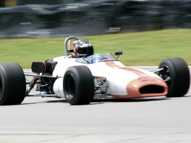 In this image, we can see a racing car, there is a person sitting in the car and wearing a helmet....