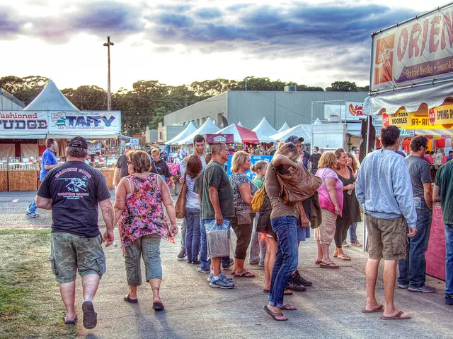 This image is clicked outside. There are so many stalls in the middle. There are so many persons...