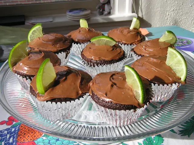 In this image there are chocolate muffins with slices of lemon on it on the plate on a table. In...