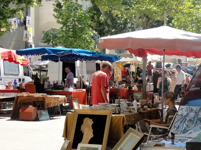 There is a woman sitting on chair and there is a person standing and we can see frames. We can see...