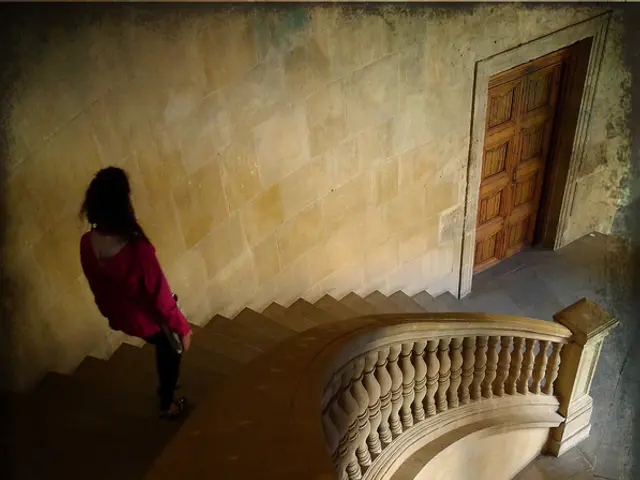 This picture describes about inside view of a building, in this we can see a woman and few stairs.