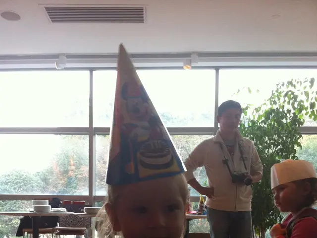 There is one kid wearing a birthday cap at the bottom of this image. There are two other persons on...