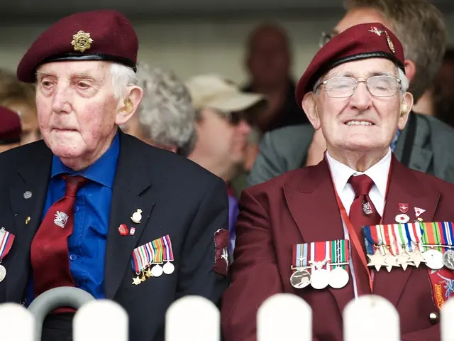 In this image I can see number of people are sitting and here I can see both of them are wearing...