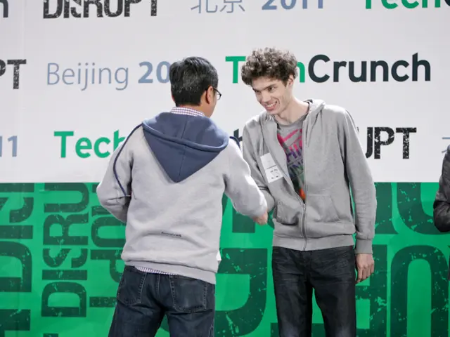 In the foreground of this image, there are two men standing and shaking their hands. On the right,...