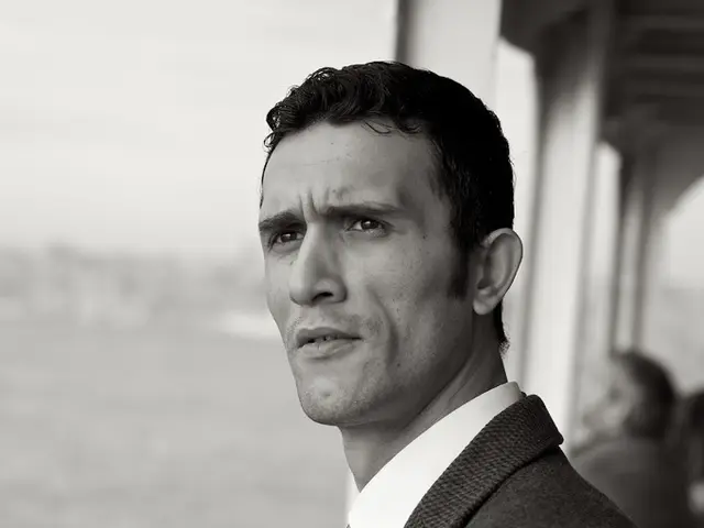 In this image in the foreground there is one person, and in the background there is another person...