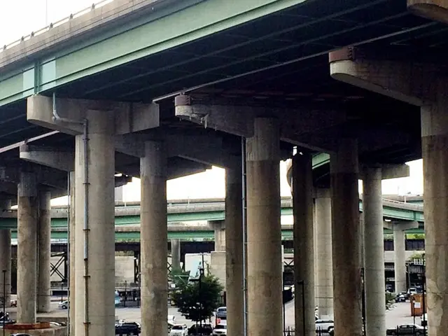 In this image we can see flyovers which are in green color and road. So many cars are parked on the...