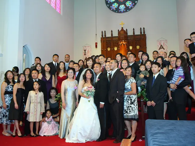 In the image there are many people standing. And to the bottom of the image there is a red carpet....