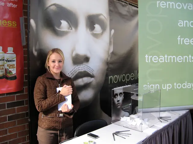 This is the woman standing and smiling. She is holding a paper in her hands. This is a chair. I can...