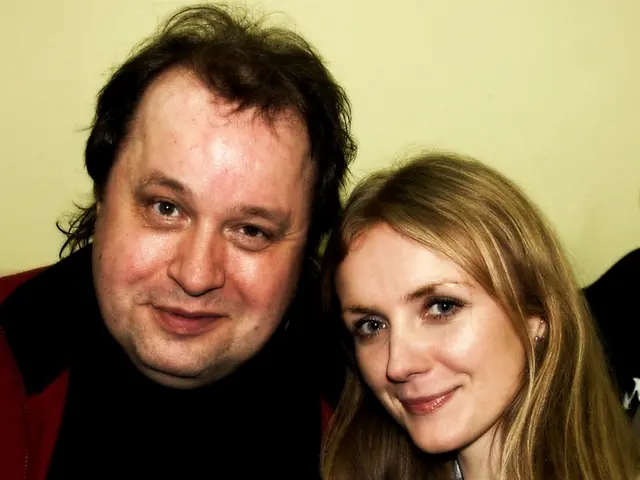 This is the man and woman smiling. I can see a badge. The background looks light yellow in color.