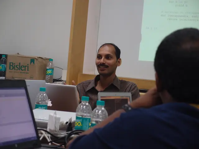 On the right hand side, there is a man in blue color t-shirt. In front of him, there is a man...