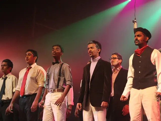 In this picture we can see a group of men standing on the stage and performing the drama. Behind...