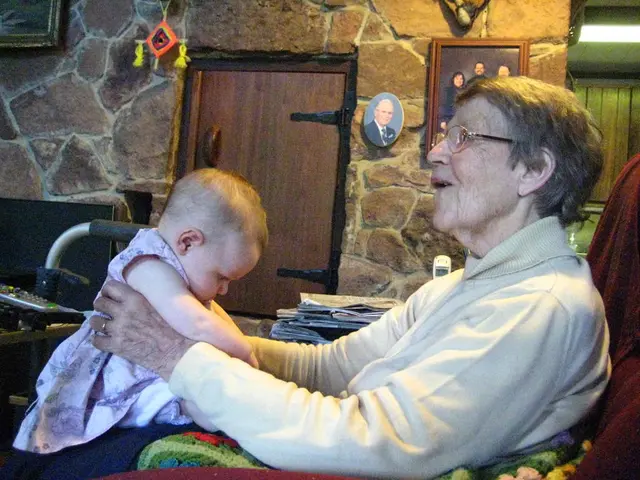 In the picture there is a person playing with a baby by putting her on the lap and behind the...