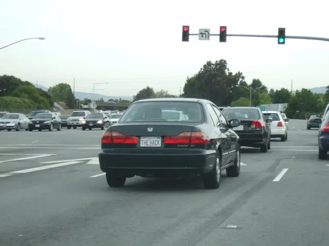 In this image we can see a road. On which there are many vehicles. In the background of the image...