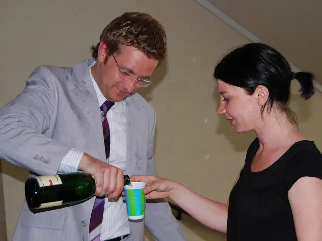 This is the picture of a guy wearing suit and holding the bottle and a lady in black dress.