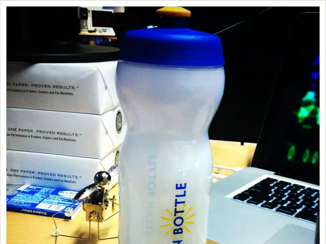 In this image I can see a bottle, a laptop and a keyboard. I can also see few more stuffs over...