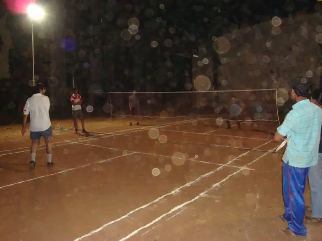 In the image there is a street light on the left side corner and few men playing volleyball on the...