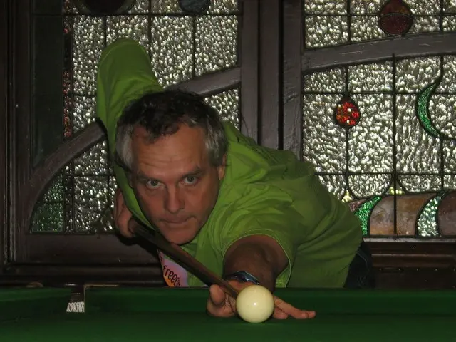 In the foreground of this picture, there is a man playing snooker and in the background, there is a...