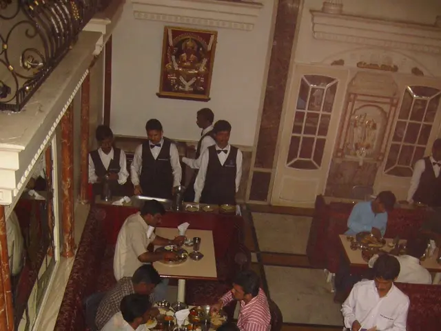 There are so many sitting in a chairs and eating food on tables and few people standing at one...