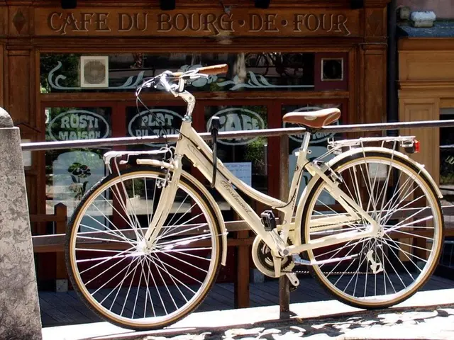 In this picture there is a white color cycle parked on the footpath. Behind there is a pipe...