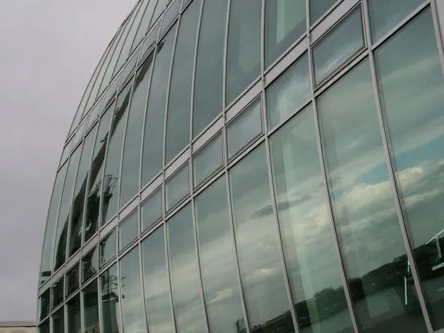 In this picture there is a huge glass corporate building. Behind there is a blue sky.