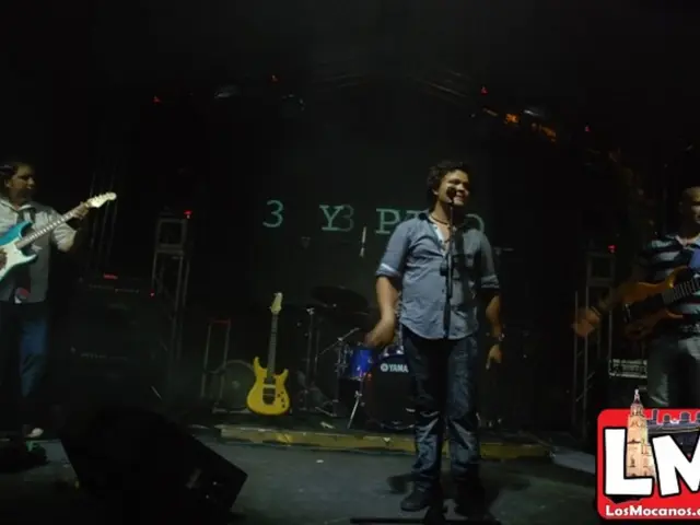 Here we can see a three persons are performing on a stage. They are playing a guitar and singing on...