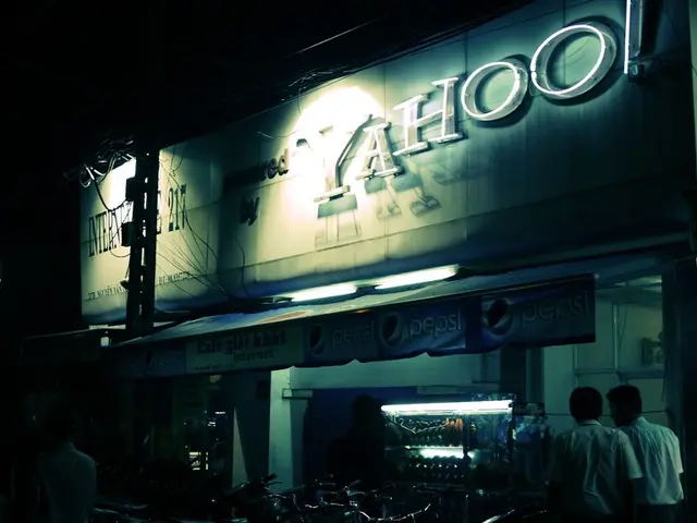 In this image we can see a building with text, there is an advertising board, a shed attached to...