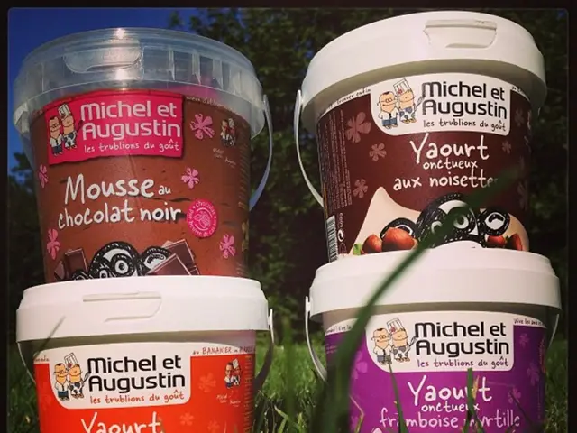 In this image few buckets are on the grassland. Buckets are kept one upon the other. Background...