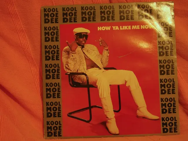 This is a picture of a poster. In the poster there is a man sitting in chair, he is wearing a cap...