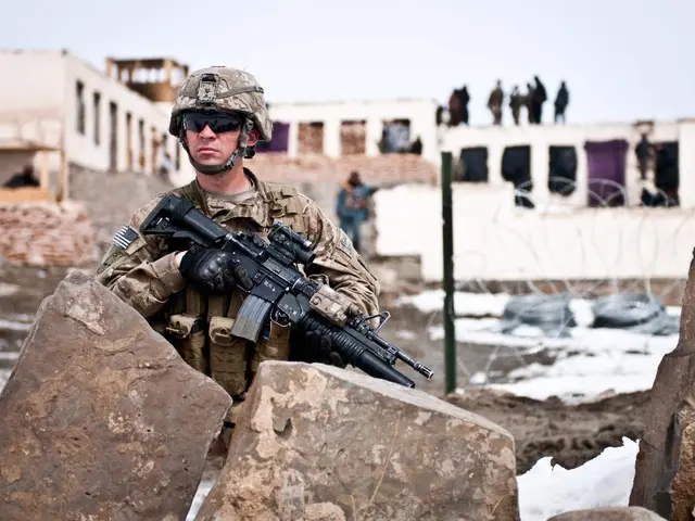 In this picture a military man holding a gun, he is looking at other side. He wore military dress...