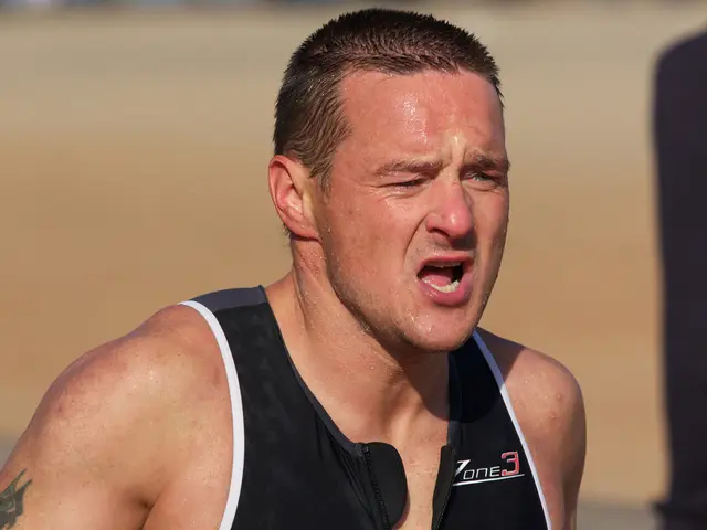 In the center of the image we can see a man sweating and he is wearing a black jacket.