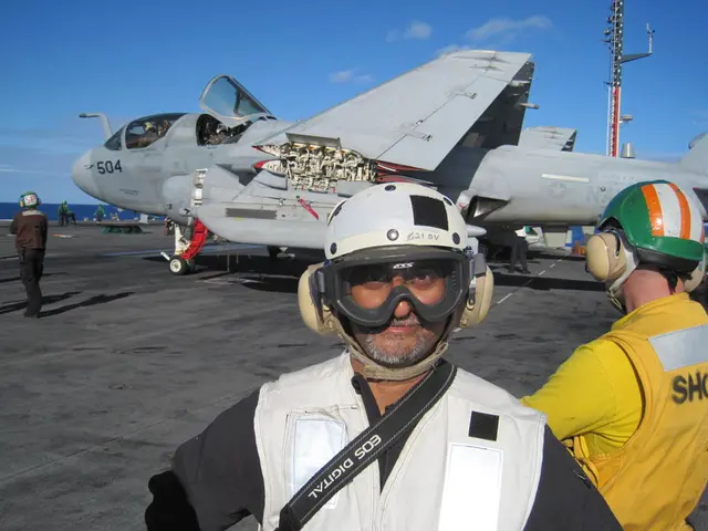 The image is taken in a warship. In the foreground of the picture there are two men. In the center...