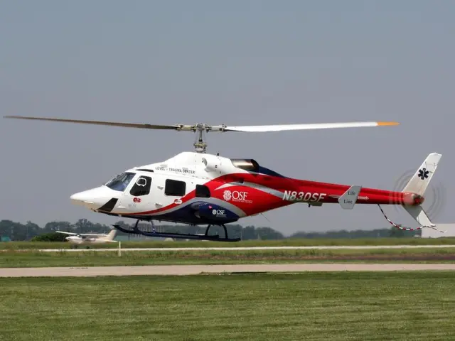 There is a helicopter in white and red color combination, flying from the helipad, near grass on...