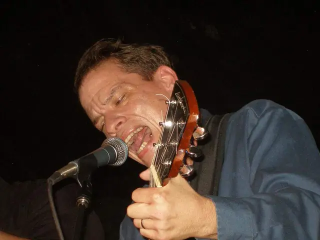 This picture shows a man playing guitar and singing with the help of a microphone