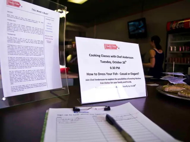 In this image there is a table, on that table there are papers, pen and posters on that posters...