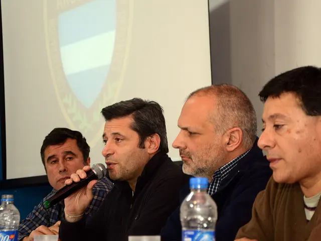 There are few people sitting here and all are men. From left second person is speaking on...