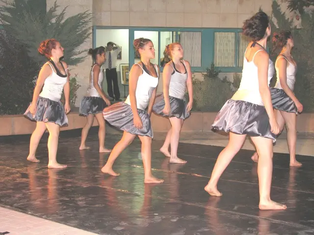 In the foreground of the picture there are six women dancing on the floor. On the left there are...