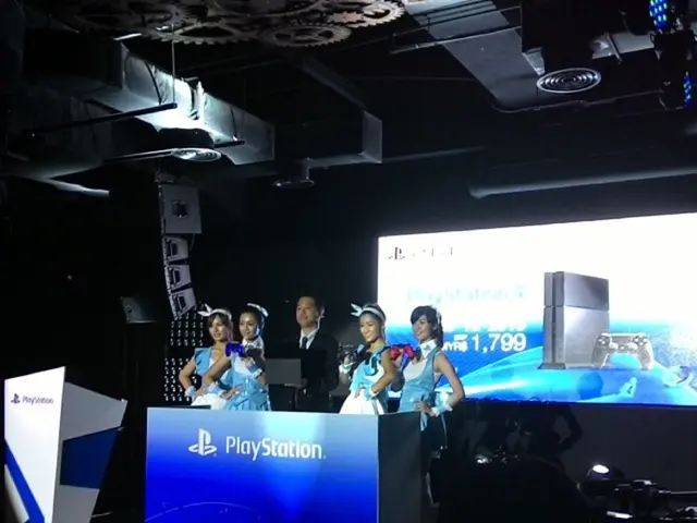 In the image we can see there are people standing on the stage near the podium and its written...