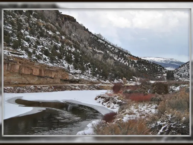 In this image we can see a mountain with trees, snow. At the top of the image there is sky, clouds....