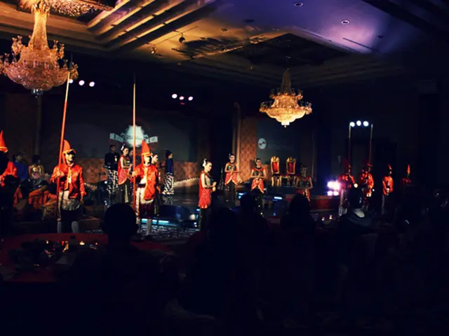 In this image we can see, a show is going on and people are sitting and watching. On the roof two...