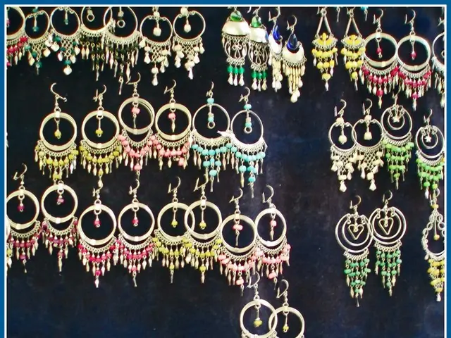 In this picture we can see many colorful earrings hanging on the blue board.