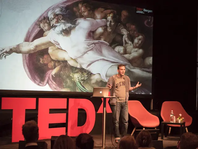 This is clicked on a stage. There is screen on the backside. There are chairs and there is a person...