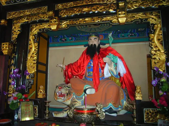 In the image there is a statue of chinese monk with colorful cloth around him sitting on a tiger...